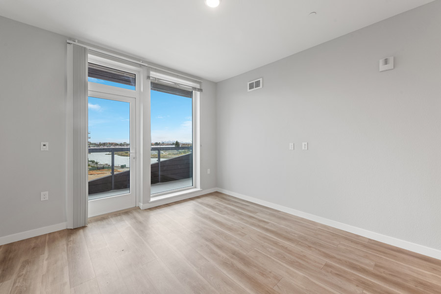 07_livingroom Open living room with balcony access and views of the surrounding waterfront area.