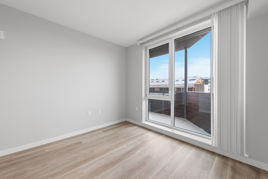 13_bedroom Bedroom with wood-look flooring and sliding glass door leading to private balcony.