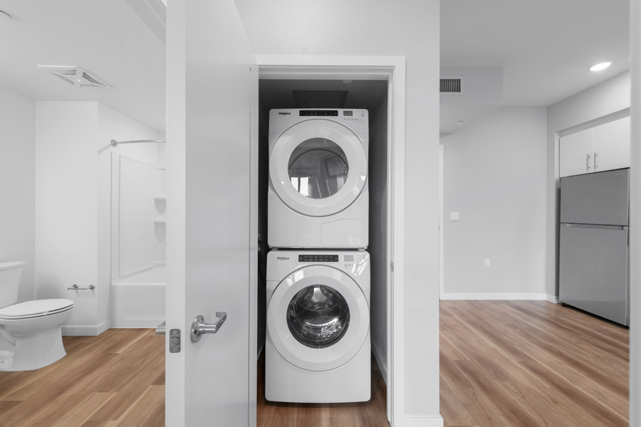16_laundry In-unit laundry area with stacked washer and dryer adjacent to bathroom.