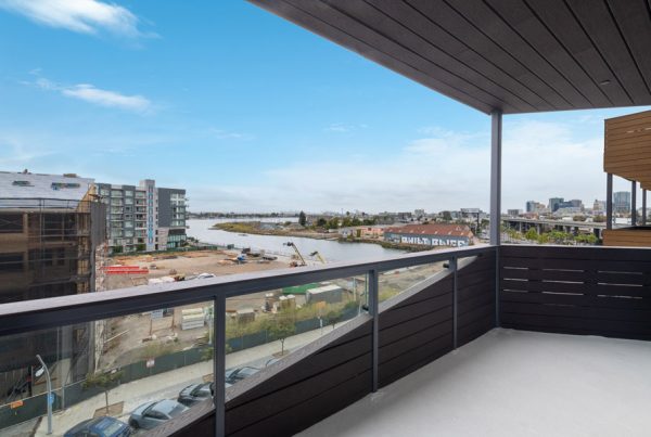Private balcony with glass railing and waterfront views of surrounding neighborhood.