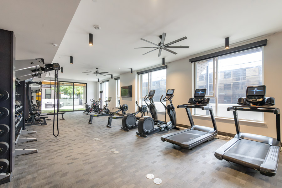 61_gym Fitness center with treadmills, stationary bikes, strength equipment, and large windows.