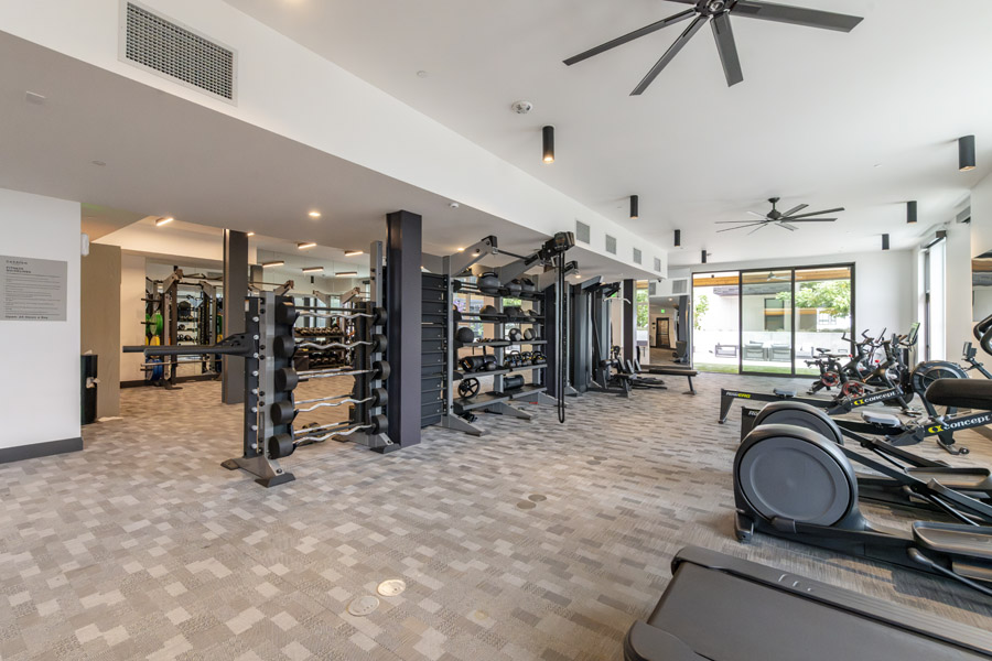 62_gym Fitness center with cardio equipment, weight machines, and large windows.
