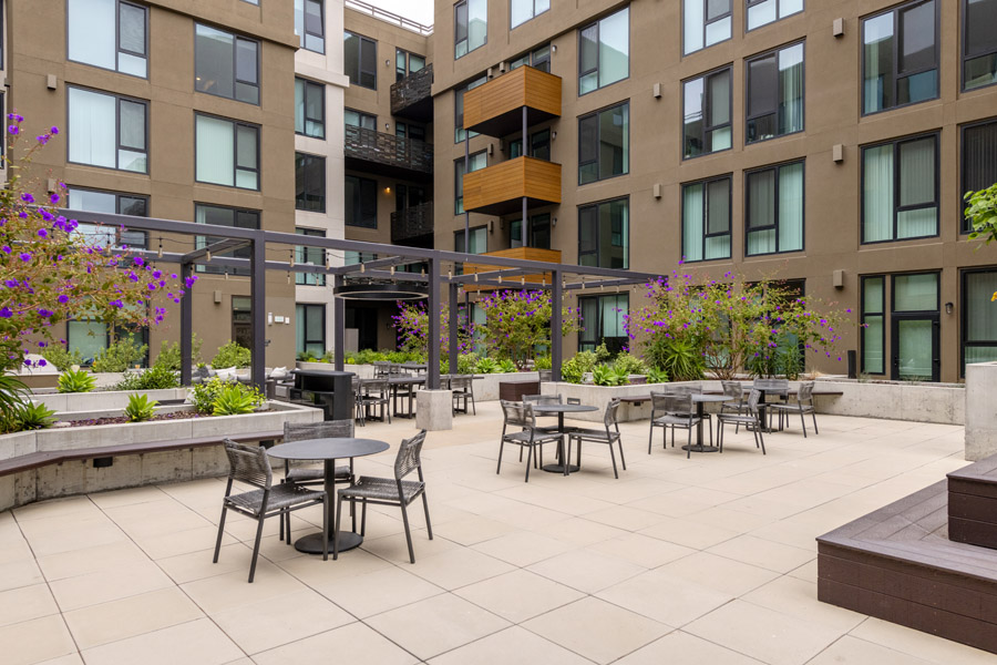 65_courtyard Shared courtyard with outdoor dining tables, landscaping, and resident seating areas.