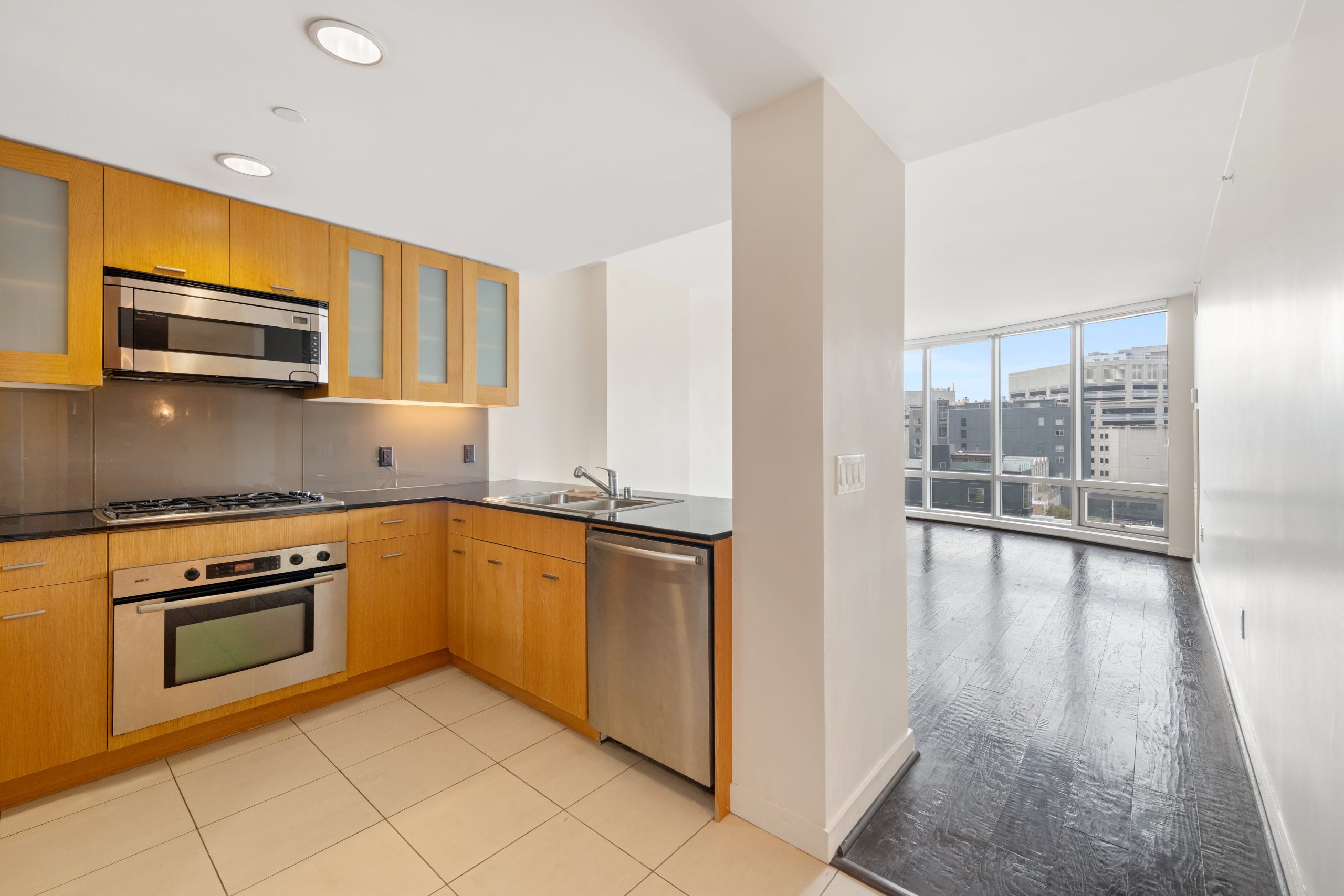 Open kitchen with stainless steel appliances, granite countertops, and city views.