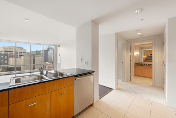 Modern kitchen with stainless steel appliances, wood cabinetry, and tile flooring.