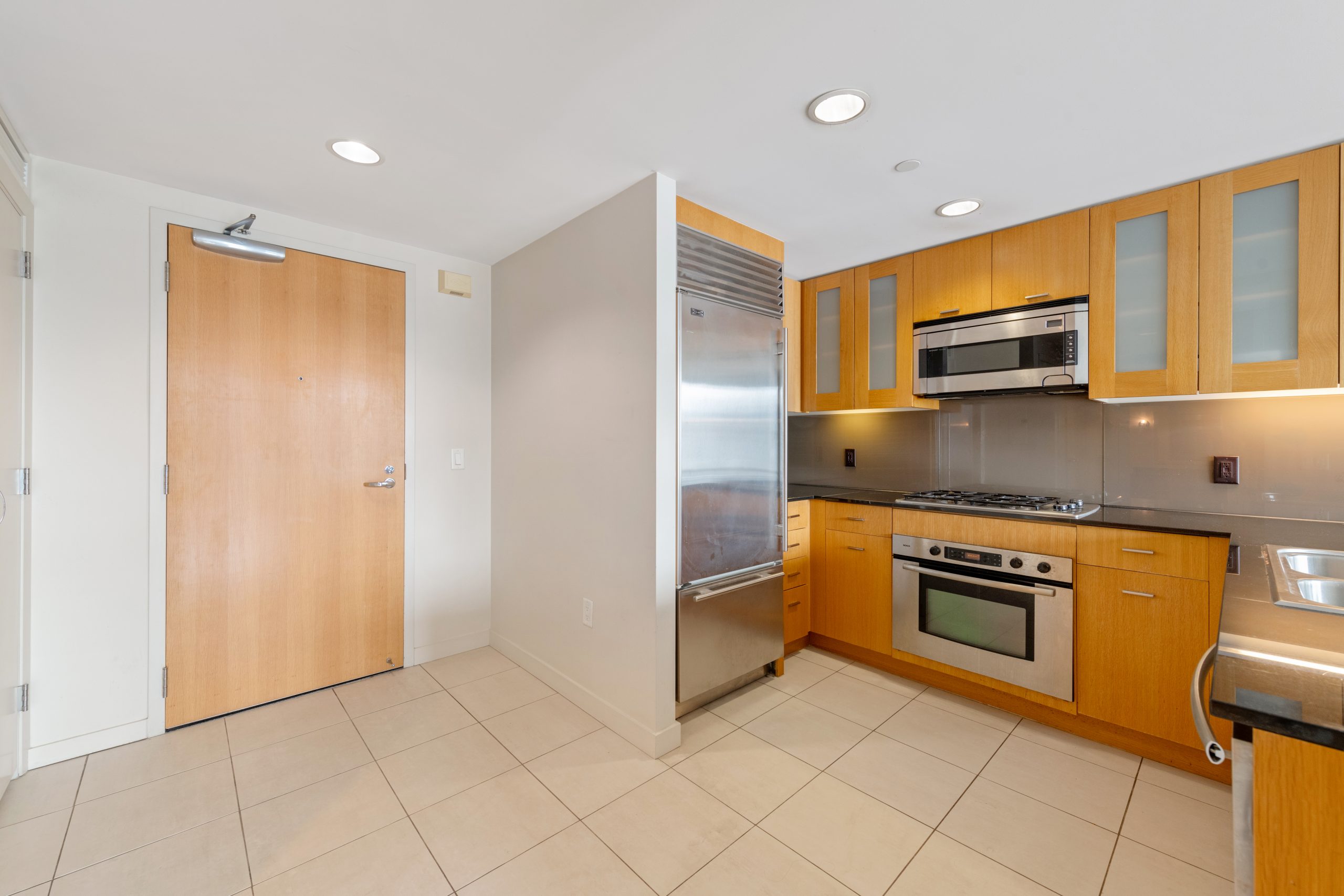 Galley kitchen with granite countertops, stainless steel appliances, and wood cabinetry.