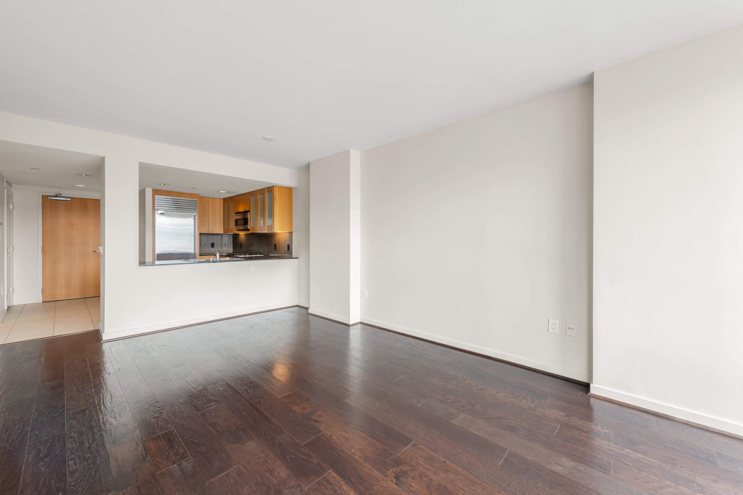 Living area with floor-to-ceiling windows, dark hardwood floors, and city views.