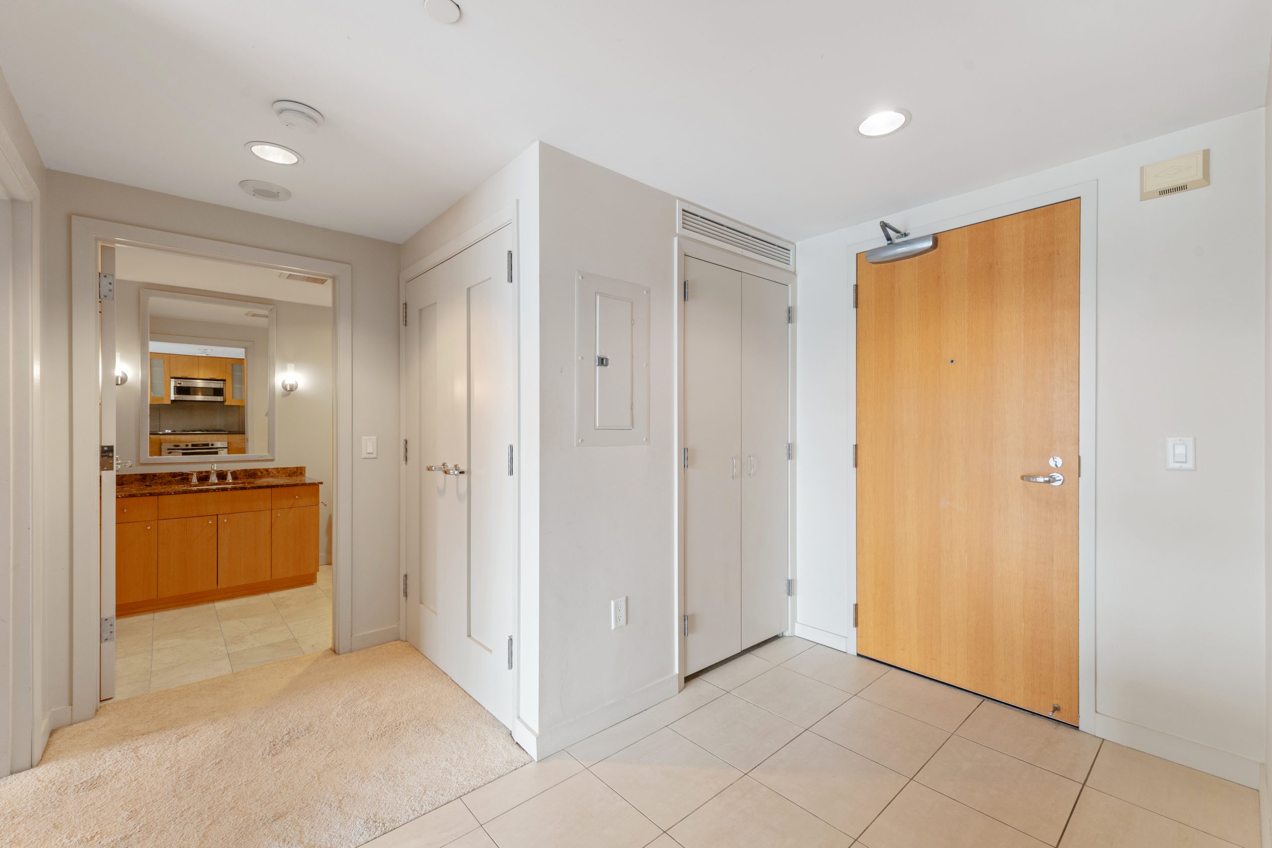Entry hallway with tile flooring, coat closet, and access to bathroom and living area.