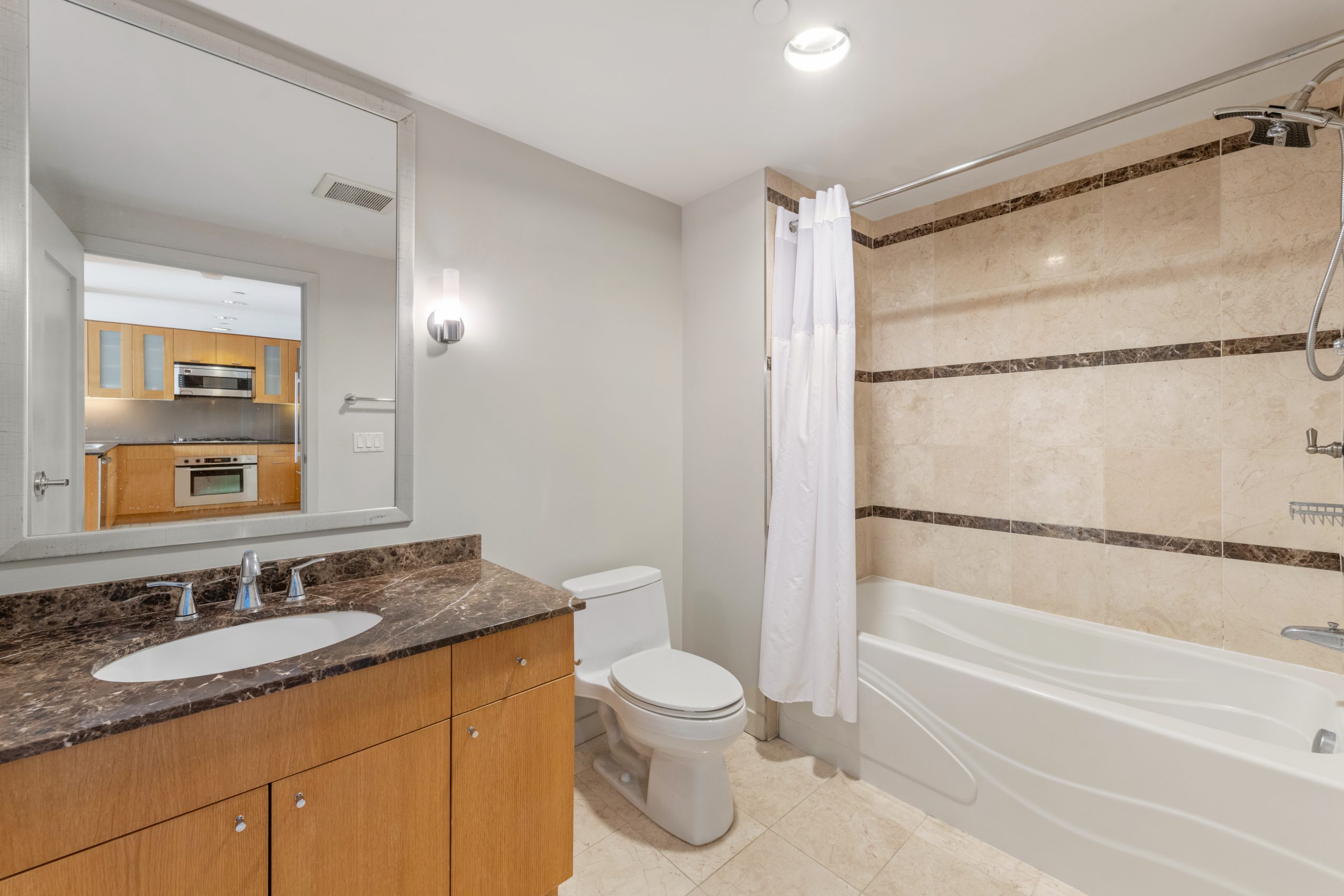 Bathroom with tub-shower combination, tile surround, and towel bar.