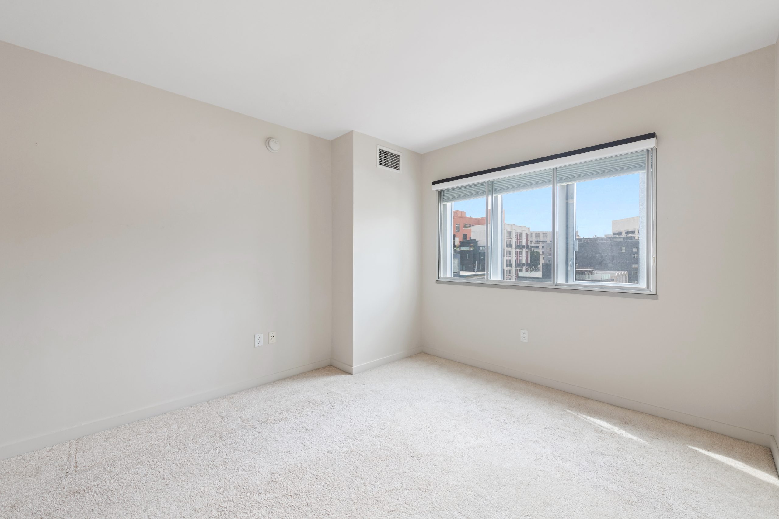 Spacious bedroom with carpeted flooring and adjacent hallway access.