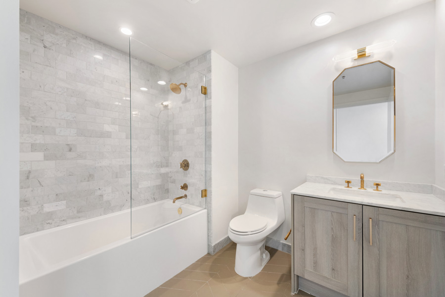 16_hallbath Bathroom with marble vanity, gold-tone fixtures, and decorative mirror.