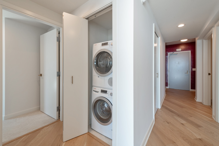 24_laundry In-unit laundry closet with stacked washer and dryer in hallway.